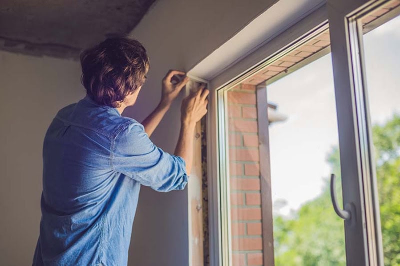 man-fixing-window-for-heat-gain-prevention