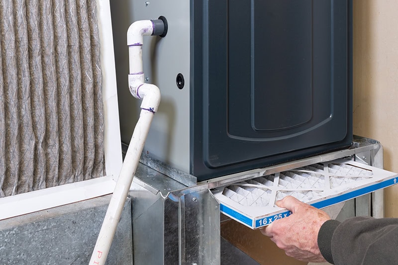 Man replacing dirty furnace filter in home.