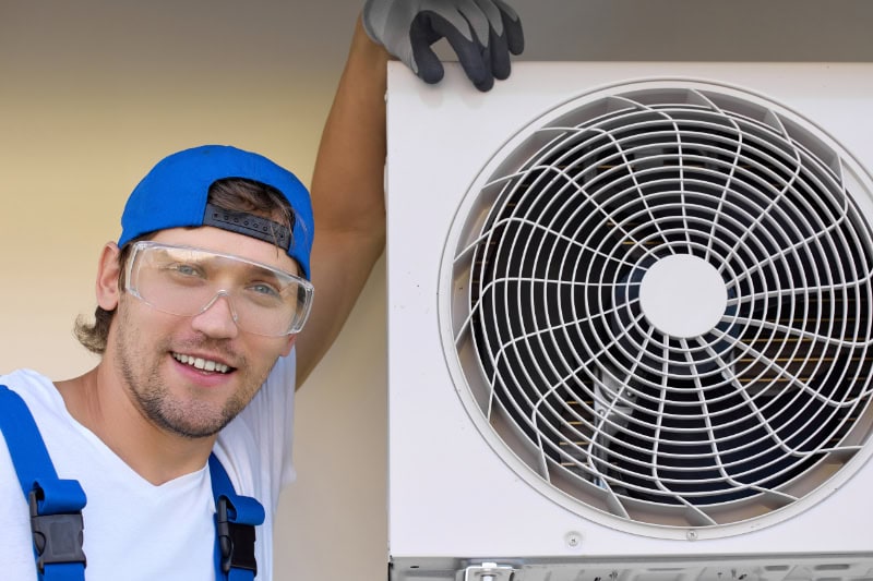 Installing New HVAC Equipment? Consider These Tips! Satisfied master installer smiles at the camera after mounting the outdoor air conditioner.