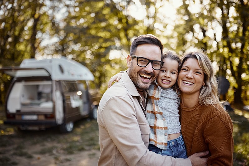 A family of three is happy outside their home.